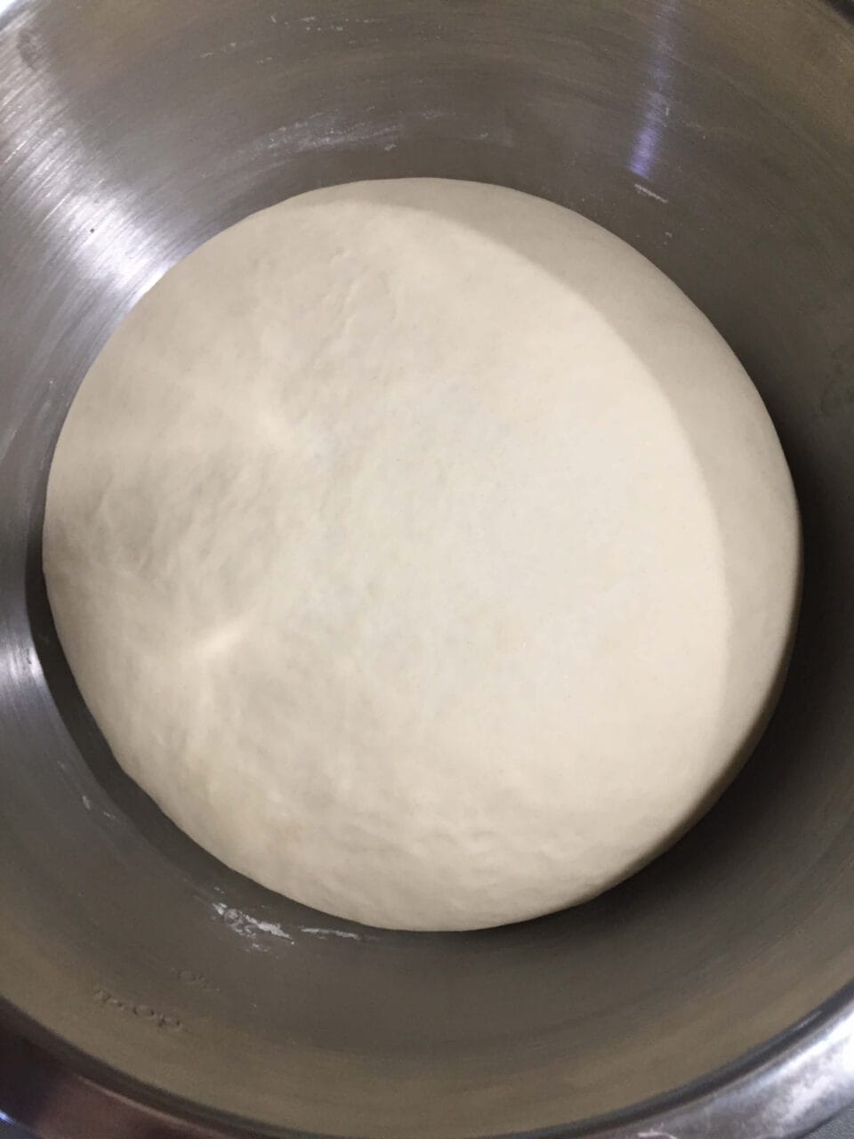 A smooth, risen dough in a stainless steel bowl.
