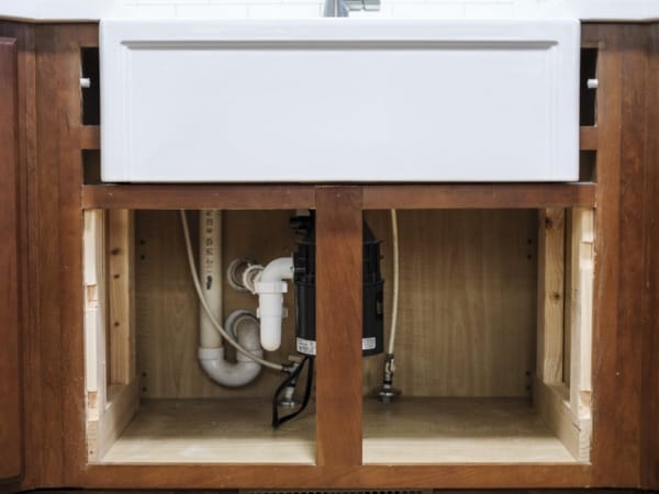 a white fireclay kitchen sink with cabinet doors off