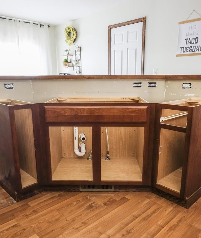 a cabinet base with sink and cabinet doors removed