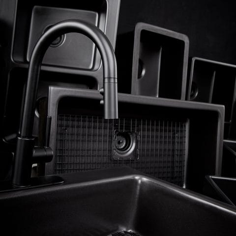 A group of rectangular matte black kitchen sinks made of fireclay.