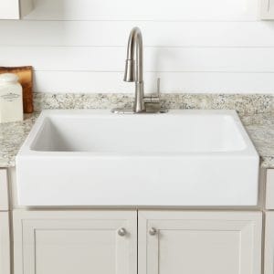 A glossy white rectangular quick-fit drop-in kitchen sink made with fireclay with nickel faucet in tan cabinets with formica countertop.