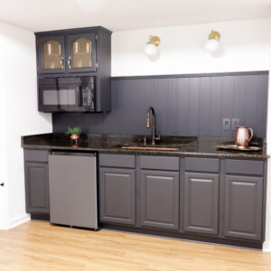 A copper rectangular undermount sink in a basement kitchenette.