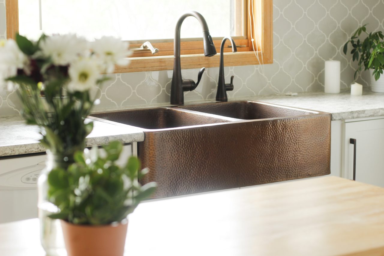 A copper rectangular undermount double basin farmhouse sink in a modern farmhouse kitchen