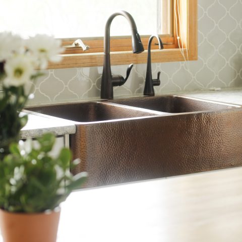 A copper rectangular undermount double basin farmhouse sink in a modern farmhouse kitchen