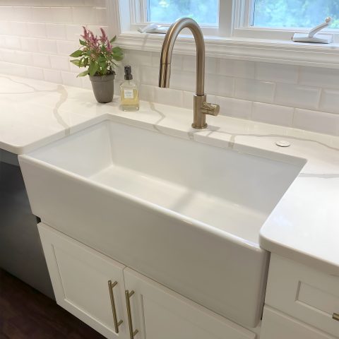 White fireclay farmhouse sink with a modern stainless steel faucet