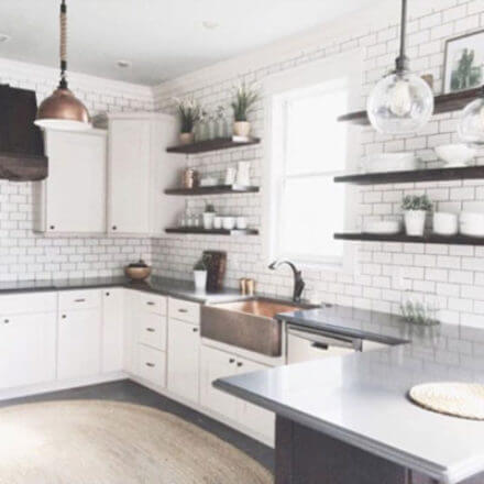 Bright, modern kitchen with white cabinets, subway tile backsplash, open wooden shelves, and a copper farmhouse sink under a large window.