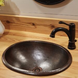 A hand hammered dual mount copper bathroom sink.