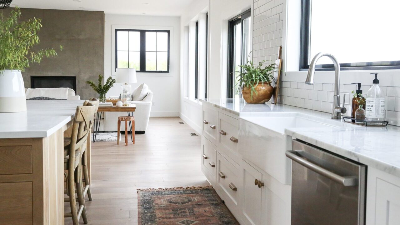 A cozy kitchen with white cabinets and wooden floors, highlighting a stylish sink that draws the eye.