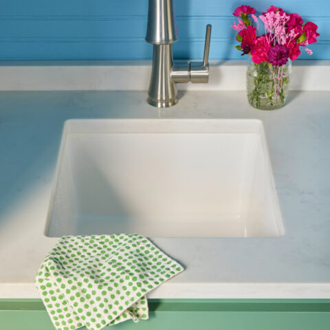 Small white fireclay bar and prep sink with stainless steel faucet and pink flower decor on countertop